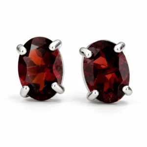 Pair of oval Garnet stud earrings set in polished 925 sterling silver on a white background.